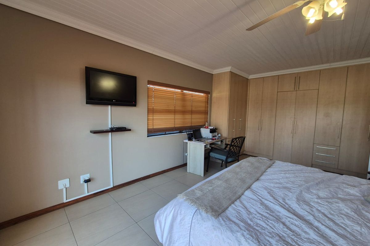 Spacious bedroom featuring extensive built-in cabinetry, tiled flooring, a ceiling fan, and large windows with venetian blinds.