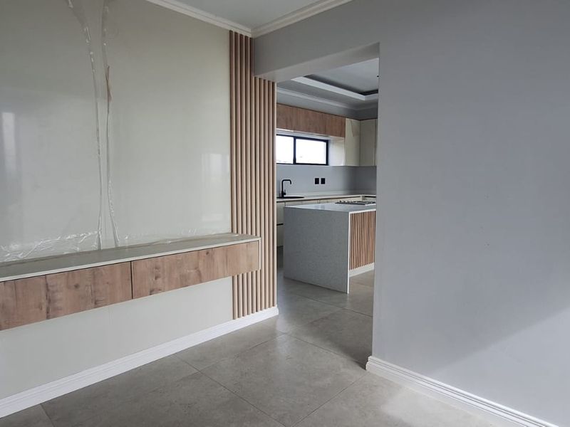 Modern open-plan living area featuring a contemporary slatted timber wall detail, sleek built-in cabinetry, and a seamless transition into a newly fitted kitchen.