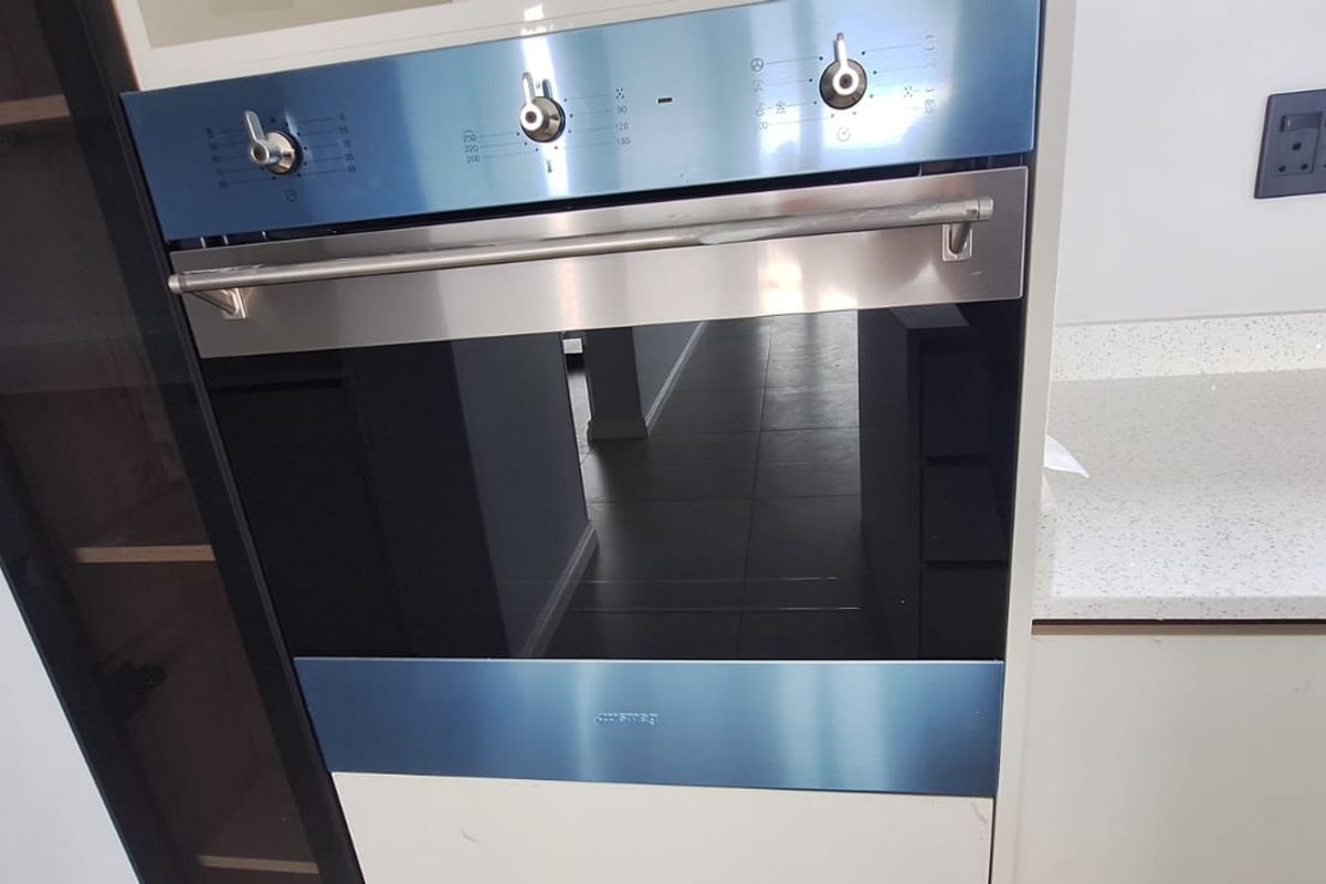 A close-up view of a modern built-in oven integrated into kitchen cabinetry with a clean quartz countertop and contemporary finishes.