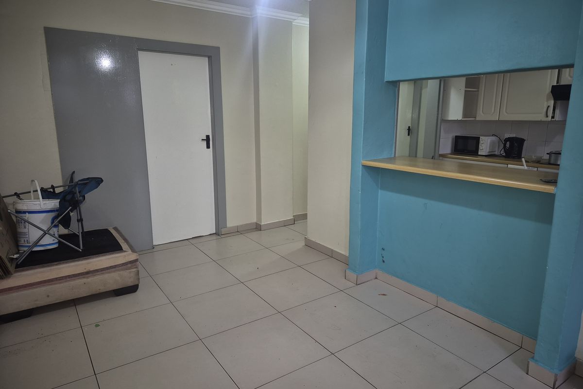 Open plan living area featuring tiled flooring and a breakfast bar pass-through to the kitchen, offering a functional layout ready for modernization.