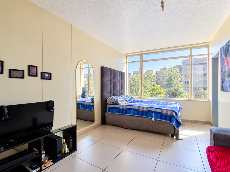 A bedroom featuring large windows that provide ample natural light, tiled flooring, and a textured ceiling.