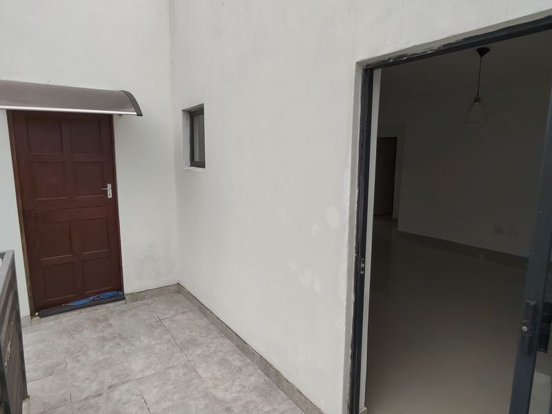 A balcony area featuring tiled flooring, a sliding glass door entrance, and a protective awning over the exterior door.