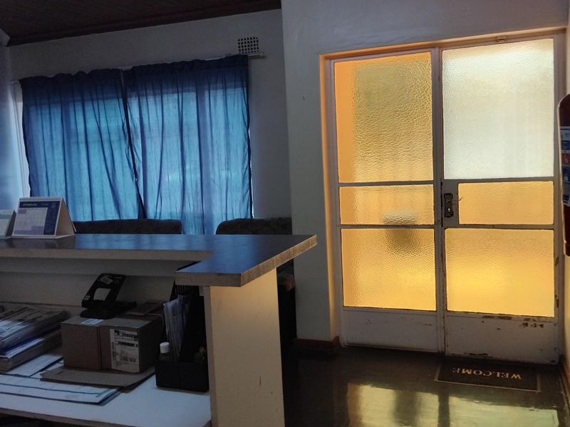 Entrance area featuring a timber ceiling, built-in reception counter, and a frosted glass door with natural light.