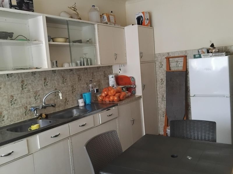 A dated kitchen featuring original cabinetry, tiled backsplash, and double bowl sink, offering potential for a modern renovation to enhance functionality and aesthetic appeal.