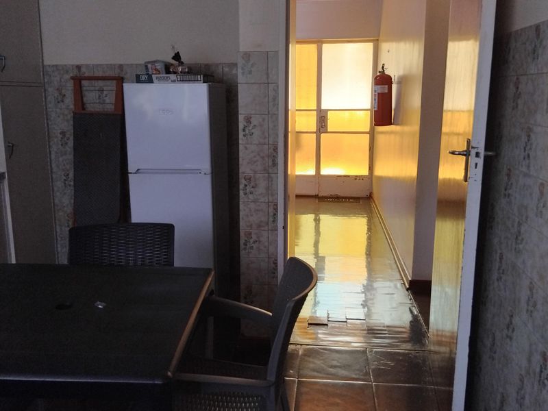 A dated kitchen area featuring tiled walls and flooring, with a doorway leading to an adjacent hallway area.