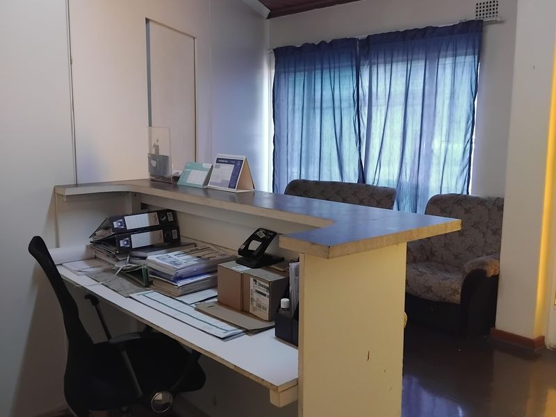 A functional office space featuring a built-in reception desk and a timber-paneled ceiling, providing a practical workspace area.