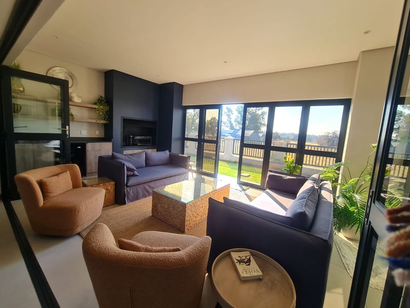 Modern living room featuring a built-in fireplace, sleek tiled floors, and expansive sliding glass doors that provide seamless access to the outdoor area.