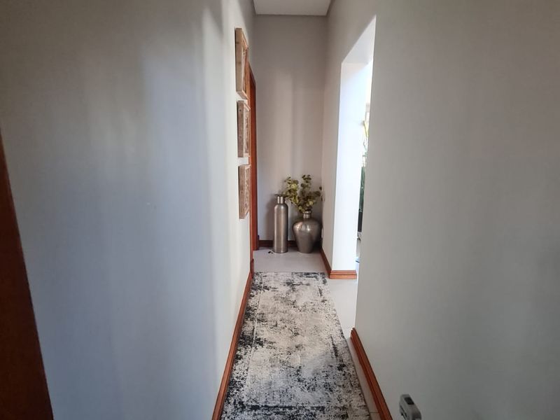 A clean and well-maintained hallway featuring neutral walls, timber skirting boards, and tiled flooring, providing a bright transition between living spaces.