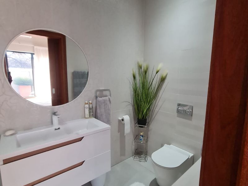 A modern, well-maintained bathroom featuring a wall-mounted vanity with integrated basin, a wall-mounted toilet with concealed cistern, and contemporary tiled finishes.