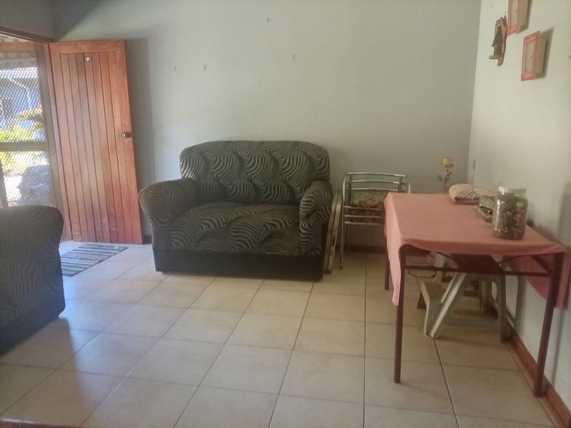 A living room area featuring tiled flooring and a timber entrance door, requiring cosmetic updates to improve the overall aesthetic and condition.