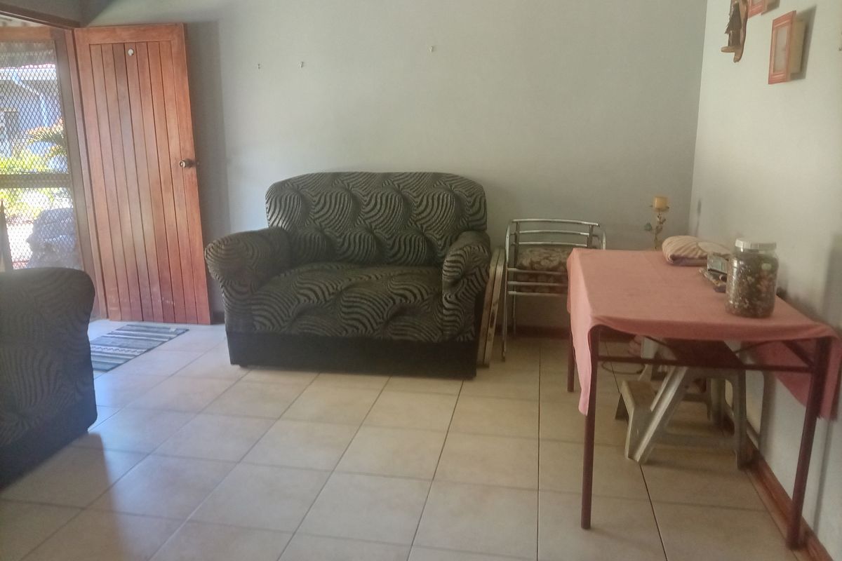 A living room area featuring tiled flooring and a timber entrance door, requiring cosmetic updates to improve the overall aesthetic and condition.