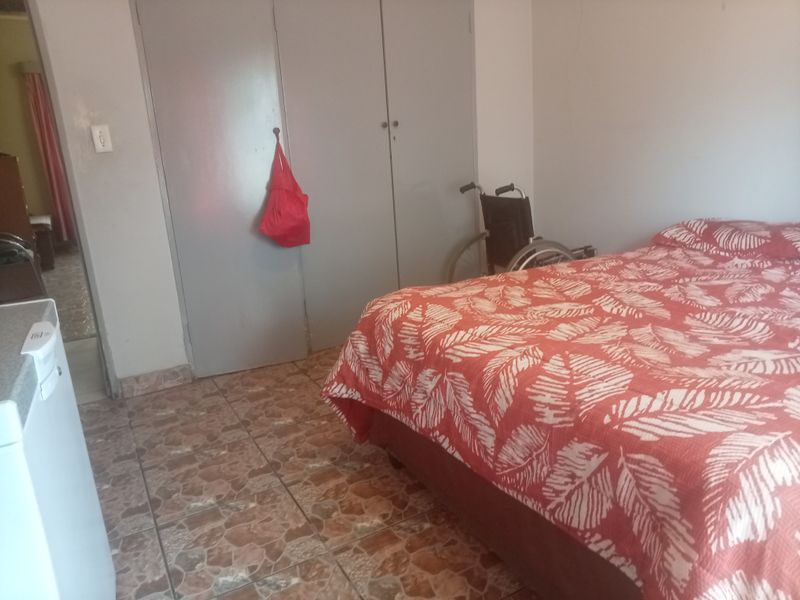 A bedroom featuring built-in cupboards and tiled flooring, providing a functional living space.