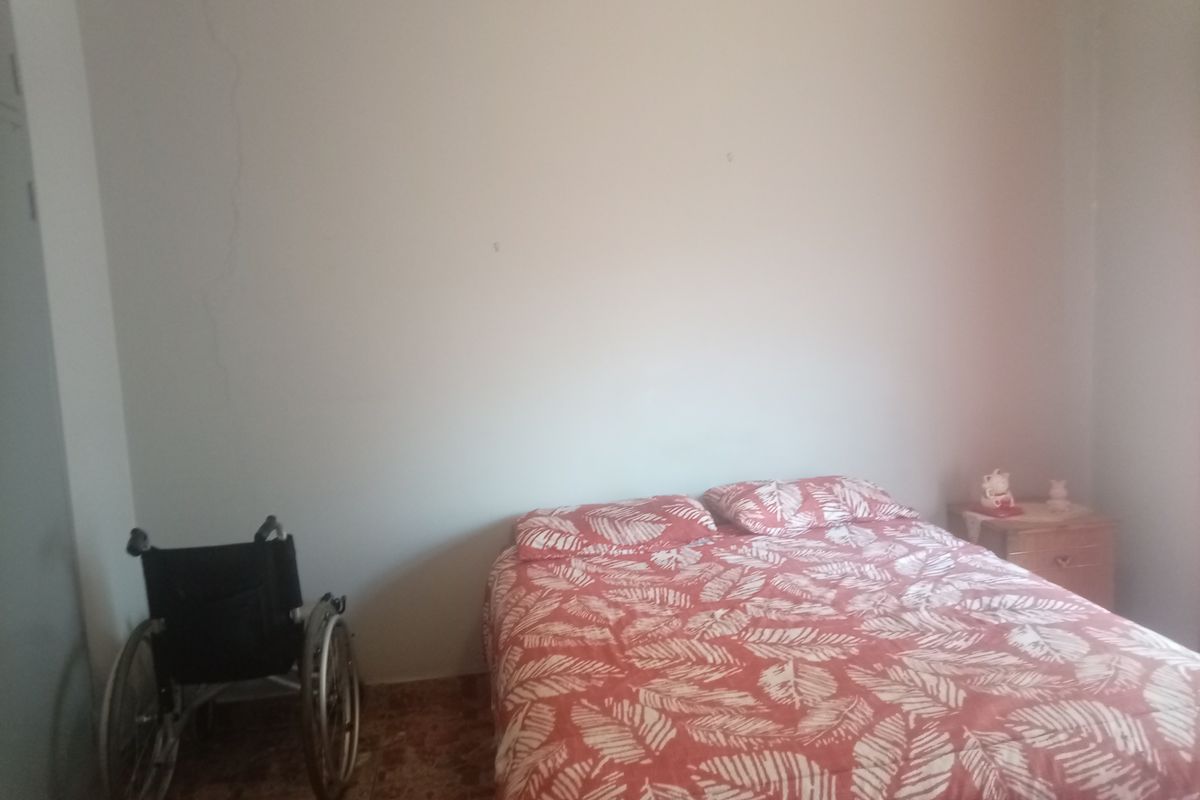 A bedroom featuring tiled flooring and a visible vertical crack on the wall, requiring maintenance and cosmetic updates.