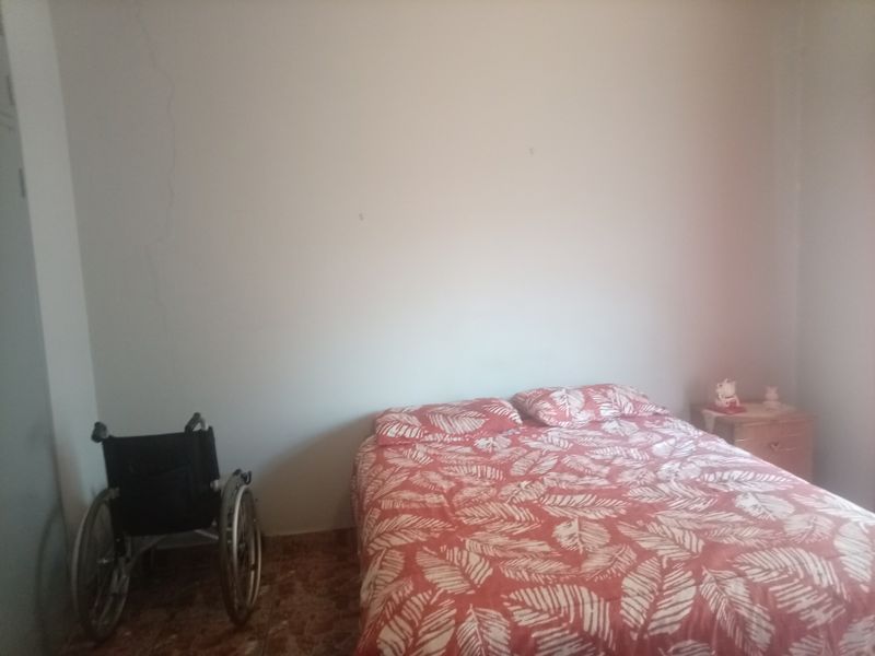 A bedroom featuring tiled flooring and a visible vertical crack on the wall, requiring maintenance and cosmetic updates.