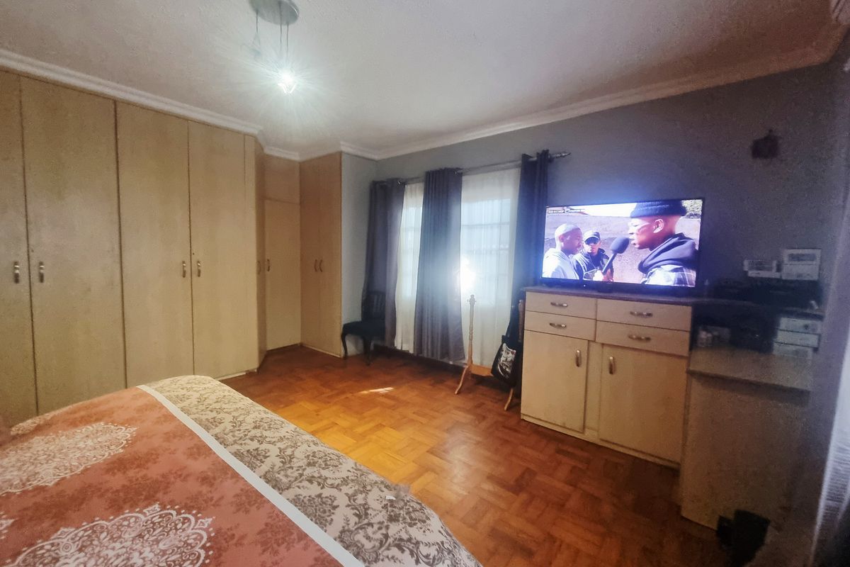 A bedroom featuring classic parquet flooring, extensive built-in wooden cupboards, and coved cornicing, offering a functional and traditional living space.