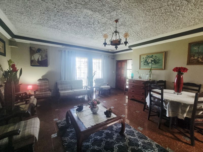 Spacious living and dining area featuring a textured popcorn ceiling, tiled flooring, and a central chandelier, offering a traditional layout with natural light.