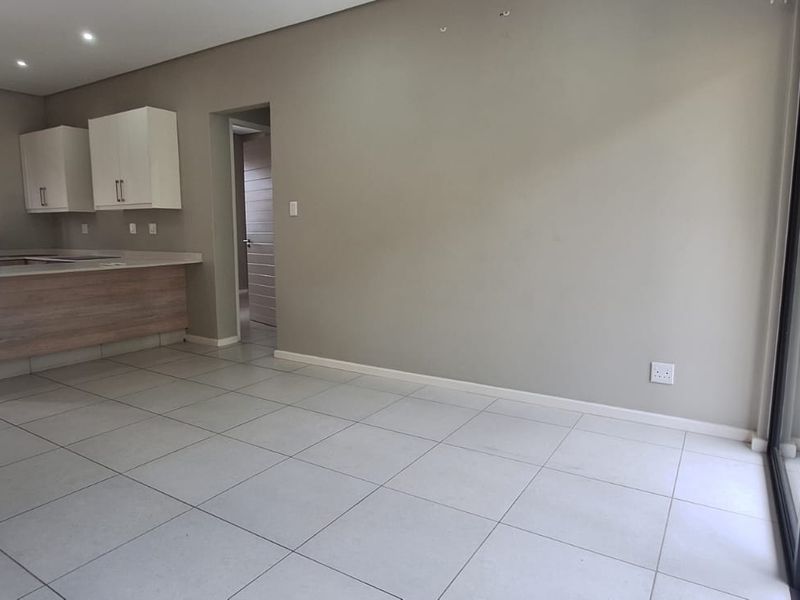 An open-plan living and kitchen area featuring modern cabinetry, tiled flooring, and large sliding glass doors leading to an outdoor space.
