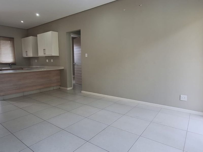 Spacious open-plan living area featuring tiled floors, recessed lighting, and a functional kitchen with built-in cabinetry and a breakfast counter.