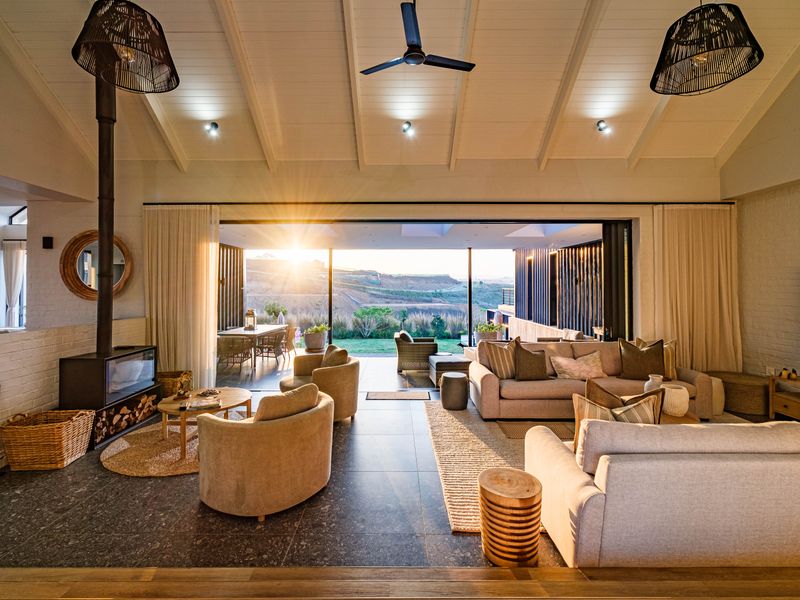 Spacious open-plan living area featuring a vaulted ceiling, modern fireplace, and seamless indoor-outdoor flow through large stacking glass doors to the patio.
