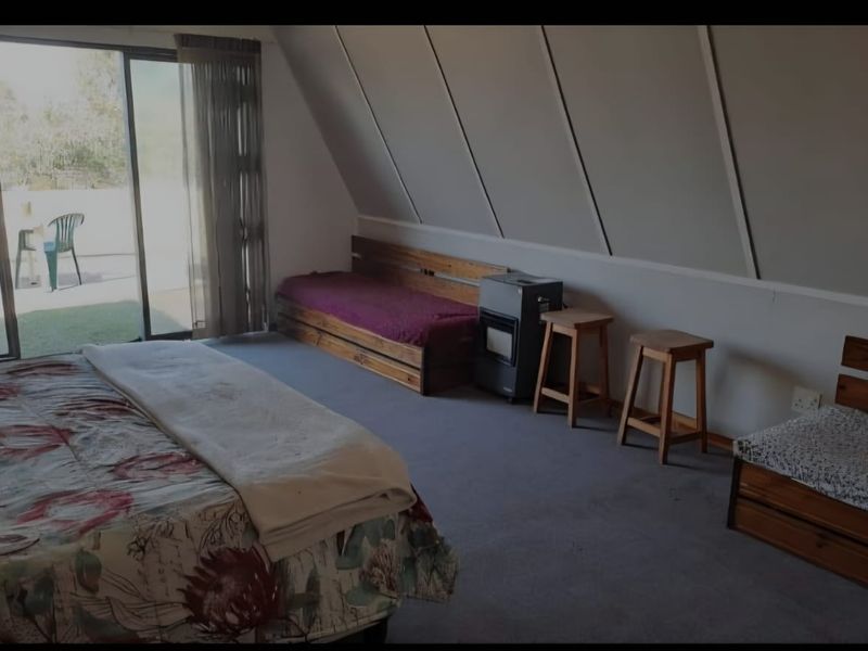A bedroom featuring a sloped ceiling, carpeted flooring, and a sliding glass door providing access to an outdoor area.