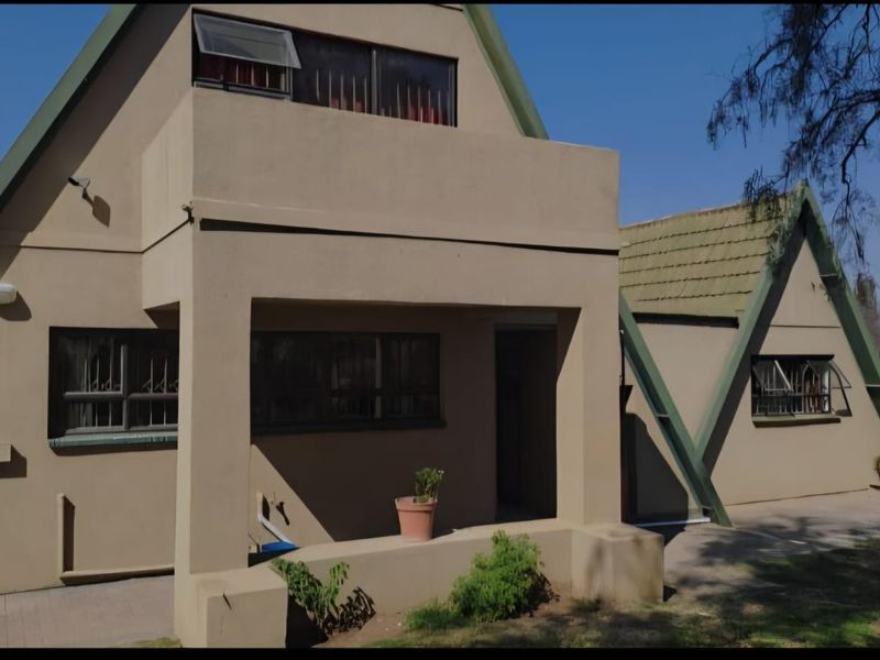 Front elevation of an A-frame style house featuring a covered porch, tiled roof, and paved walkway access.
