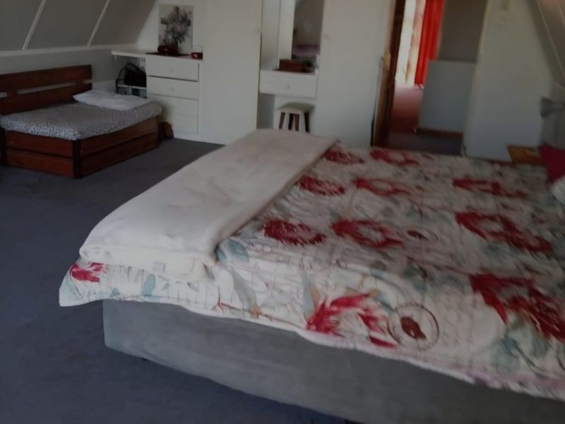 Spacious bedroom featuring a sloped ceiling, carpeted flooring, and integrated built-in wardrobe storage.