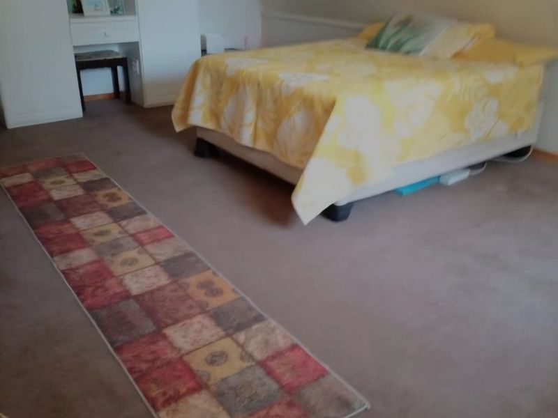 A bedroom featuring a sloped ceiling, carpeted flooring, and a built-in wardrobe unit.