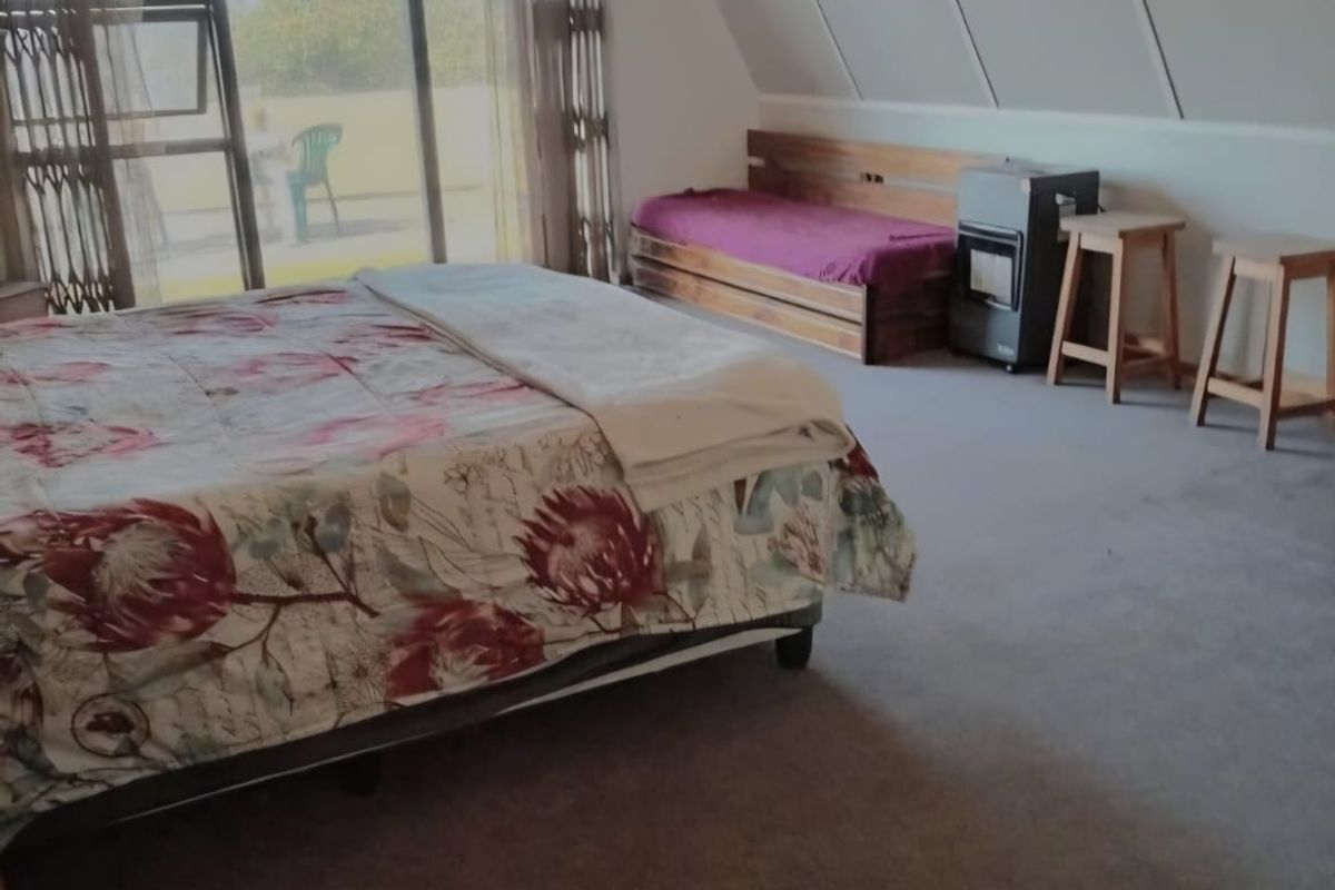 Spacious bedroom featuring a sloped ceiling, ceiling fan, and large sliding glass doors that provide access to an outdoor area.