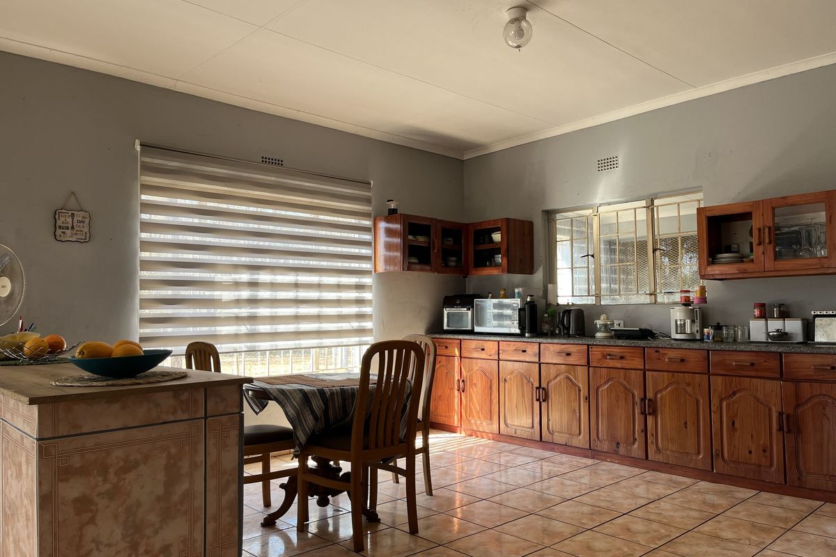 A functional kitchen featuring wooden cabinetry, tiled flooring, and a central island, offering a traditional layout with ample storage space.