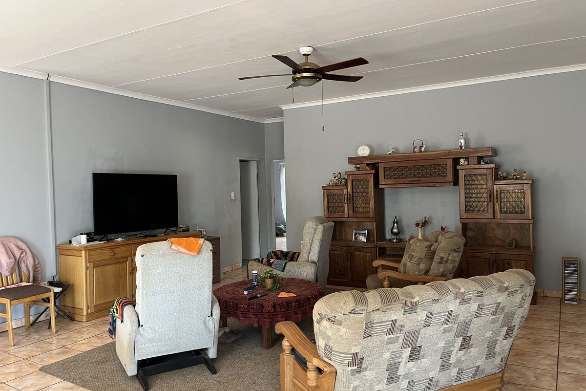 A spacious living room featuring tiled flooring, a ceiling fan, and neutral wall finishes, offering a comfortable and functional living area.