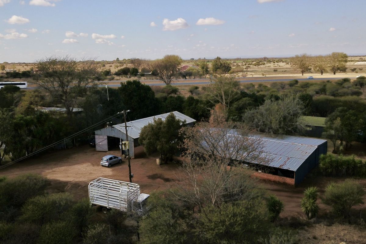 Aerial view of a small holding property featuring multiple outbuildings with corrugated metal roofs and surrounding rural landscape.