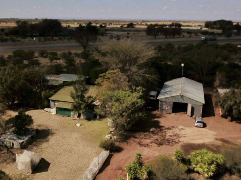 Aerial view of the small holding property featuring multiple outbuildings, workshop structures, and expansive grounds with gravel access paths.