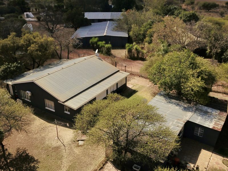 Aerial view of the small holding property featuring the main dwelling, multiple outbuildings, and surrounding garden area.