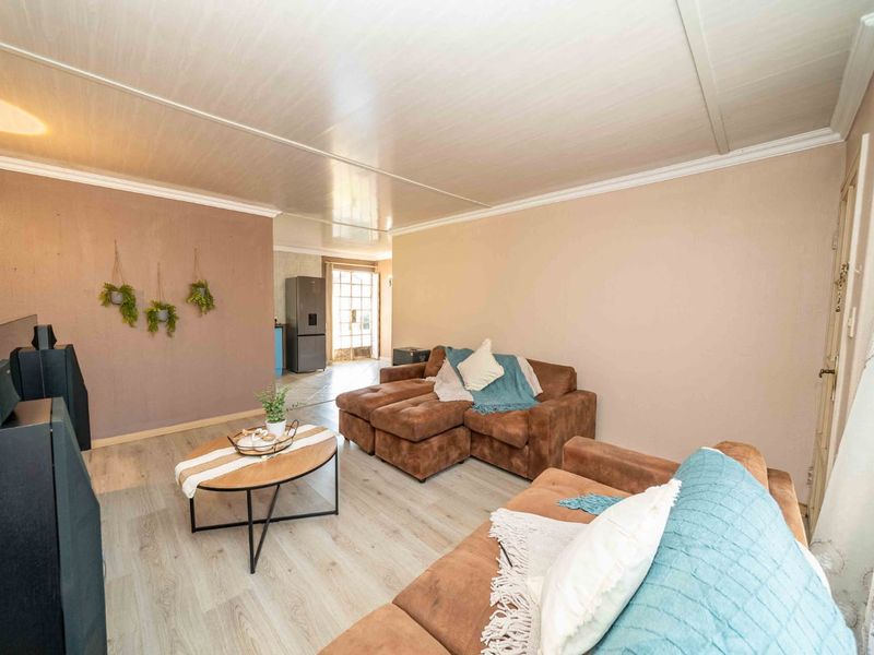 A comfortable living room featuring light-toned laminate flooring, coved ceilings, and neutral wall finishes, providing a functional and inviting space.