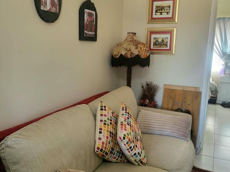 A living room area featuring tiled flooring and a view into an adjacent room.