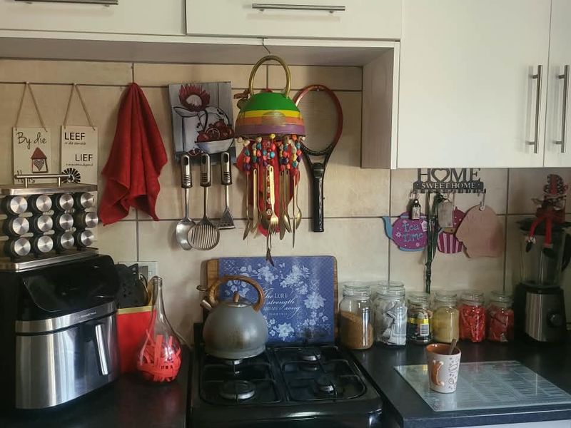 A functional kitchen area featuring white built-in cabinetry, a gas stove, and a tiled backsplash with dark laminate countertops.