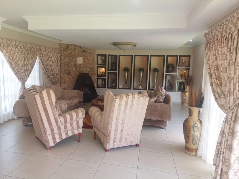 Spacious living room featuring a stone fireplace, built-in recessed wall niches, and neutral tiled flooring.
