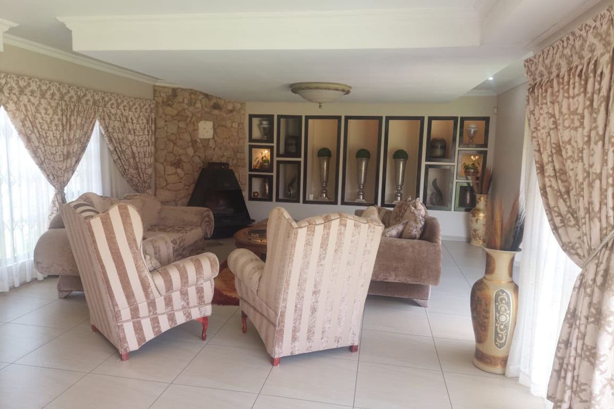 Spacious living room featuring a stone fireplace, built-in recessed wall niches, and neutral tiled flooring.