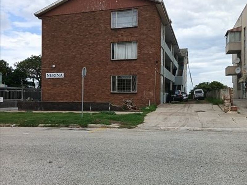 Exterior view of the Nerina apartment building featuring a brick facade, security window bars, and a concrete driveway entrance.