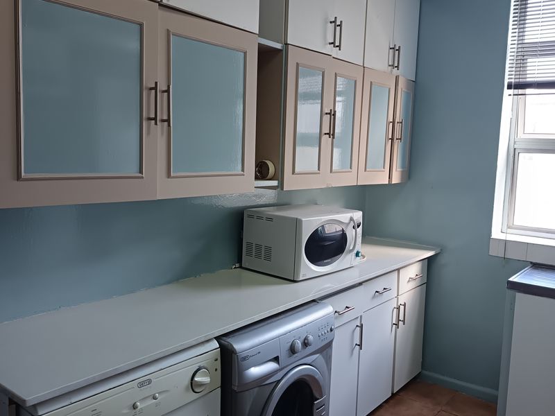 A functional laundry area featuring built-in cabinetry, tiled flooring, and dedicated space for washing appliances under a countertop.