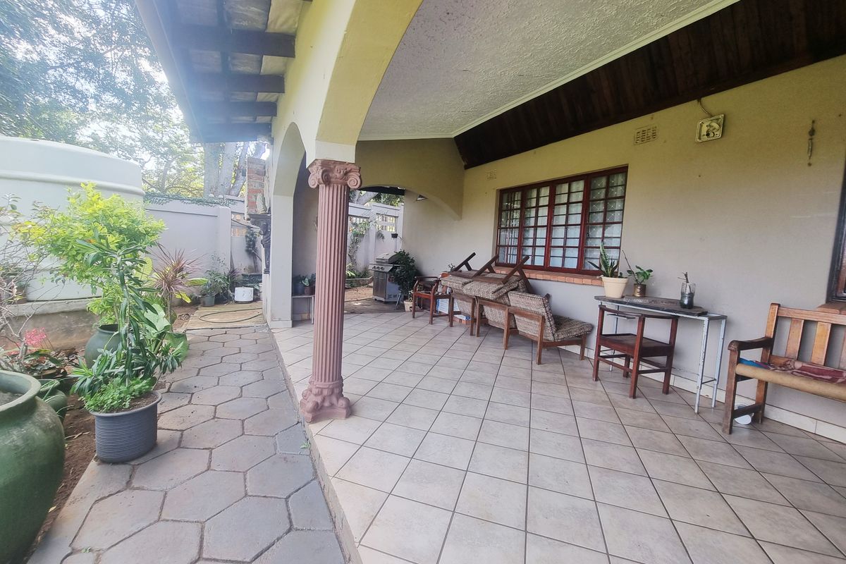 A covered patio area featuring tiled flooring, decorative columns, and timber ceiling beams, providing a functional outdoor space for relaxation.