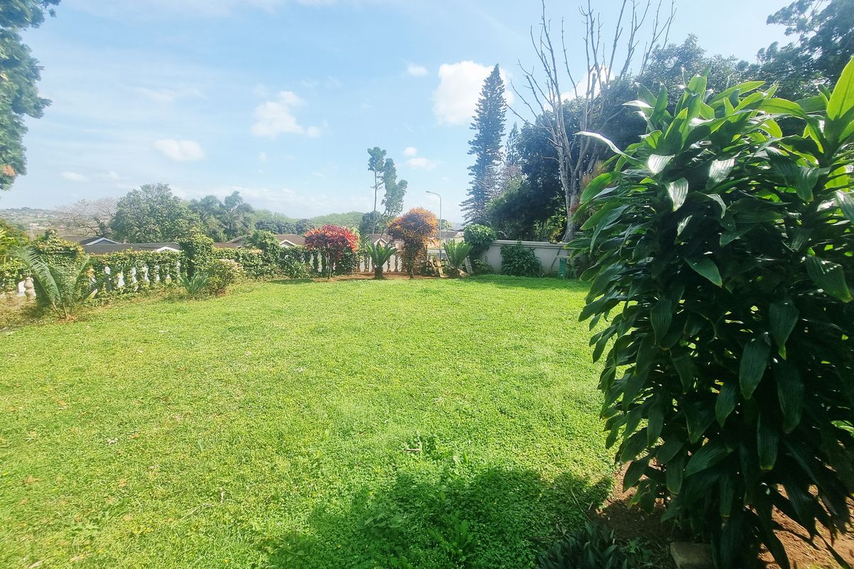 A spacious, well-maintained private garden featuring a large lawn area and established boundary wall, offering a peaceful outdoor space.