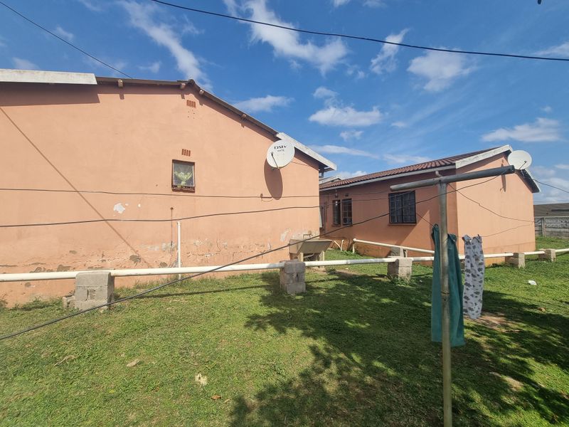Rear exterior view of the property showing the back facade, garden area, and fixed utility wash trough.