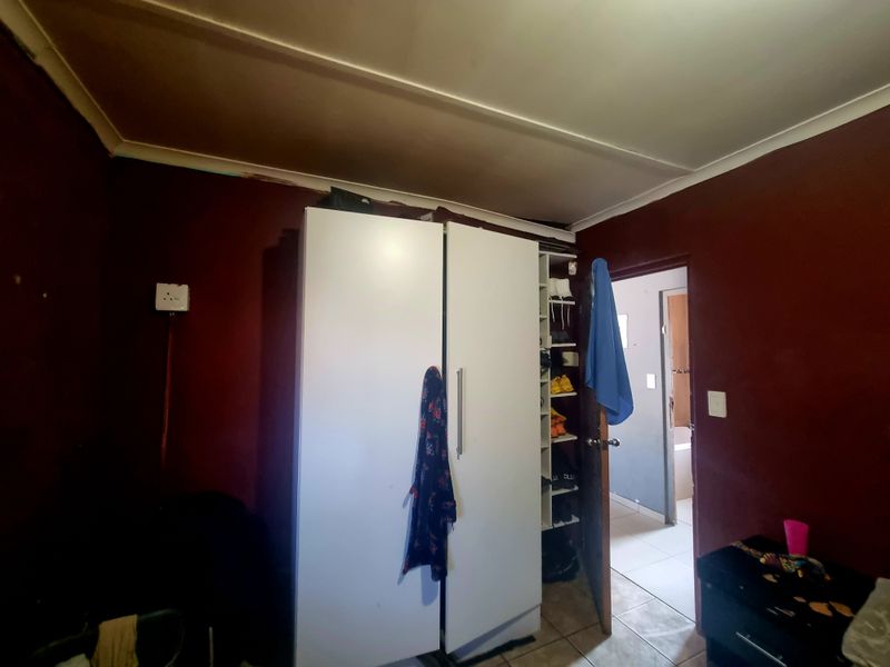 A bedroom featuring a built-in cupboard and tiled flooring, requiring cosmetic updates and repairs to the ceiling and wall finishes.