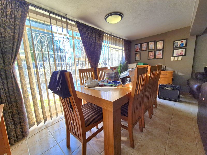 Dining room featuring tiled flooring and a large sliding glass door with security gate, providing natural light and access to the exterior.
