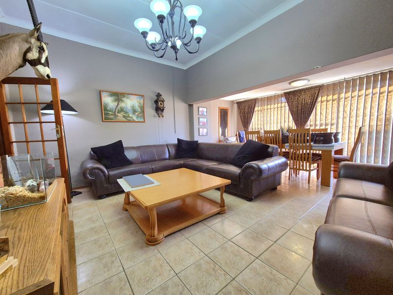 Spacious open-plan living and dining area featuring tiled flooring, coved ceilings, and large windows with vertical blinds.