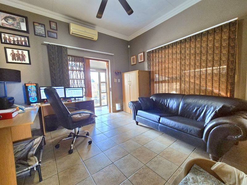 A living room featuring ceramic floor tiles, a ceiling fan, and a split-system air conditioner, with direct access to an outdoor area via a sliding door.
