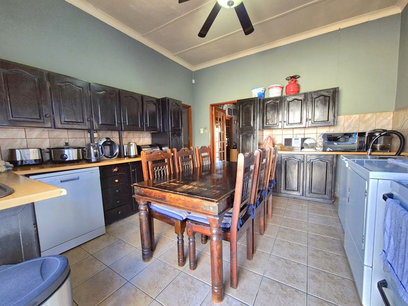 A functional kitchen featuring dark wood cabinetry, tiled flooring, and a tiled backsplash, providing a practical space for cooking and dining.