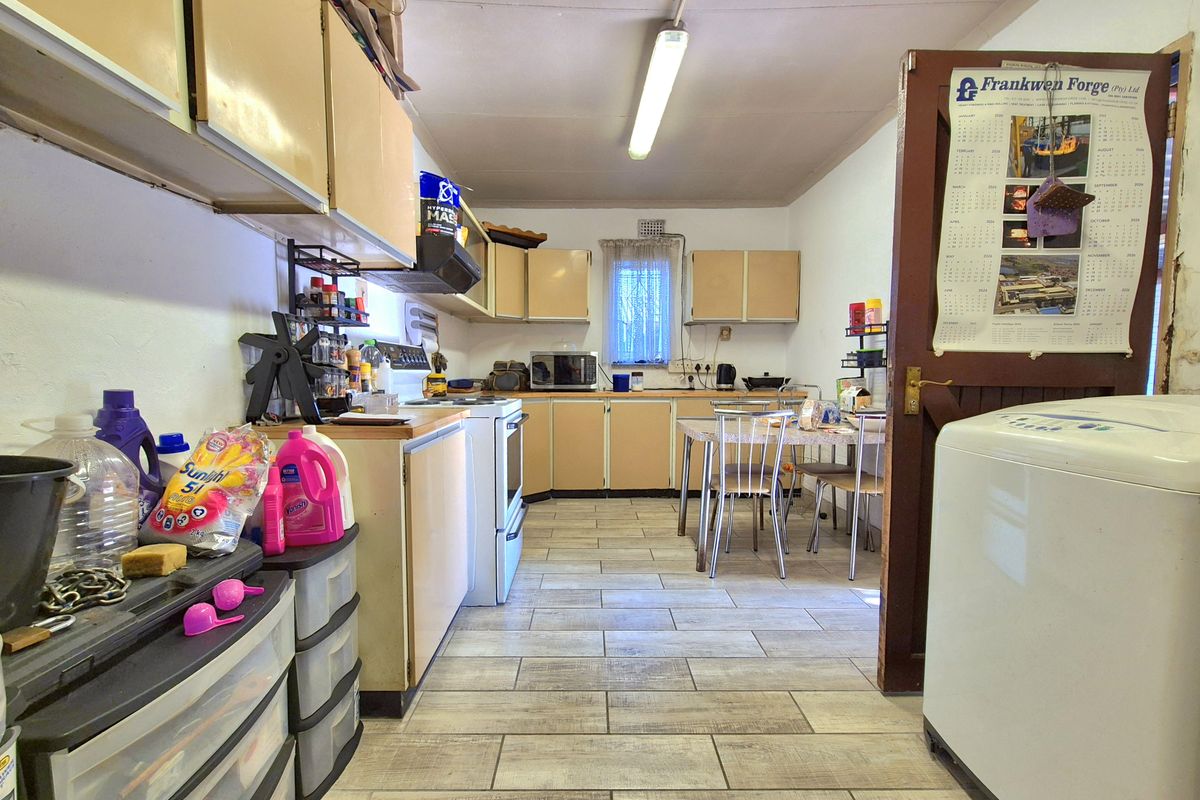 A functional kitchen featuring laminate cabinetry, tiled flooring, and a freestanding stove, offering potential for modernization and aesthetic updates.