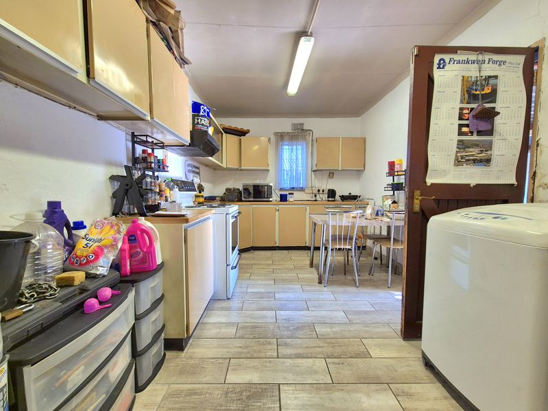 A functional kitchen featuring laminate cabinetry, tiled flooring, and a freestanding stove, offering potential for modernization and aesthetic updates.